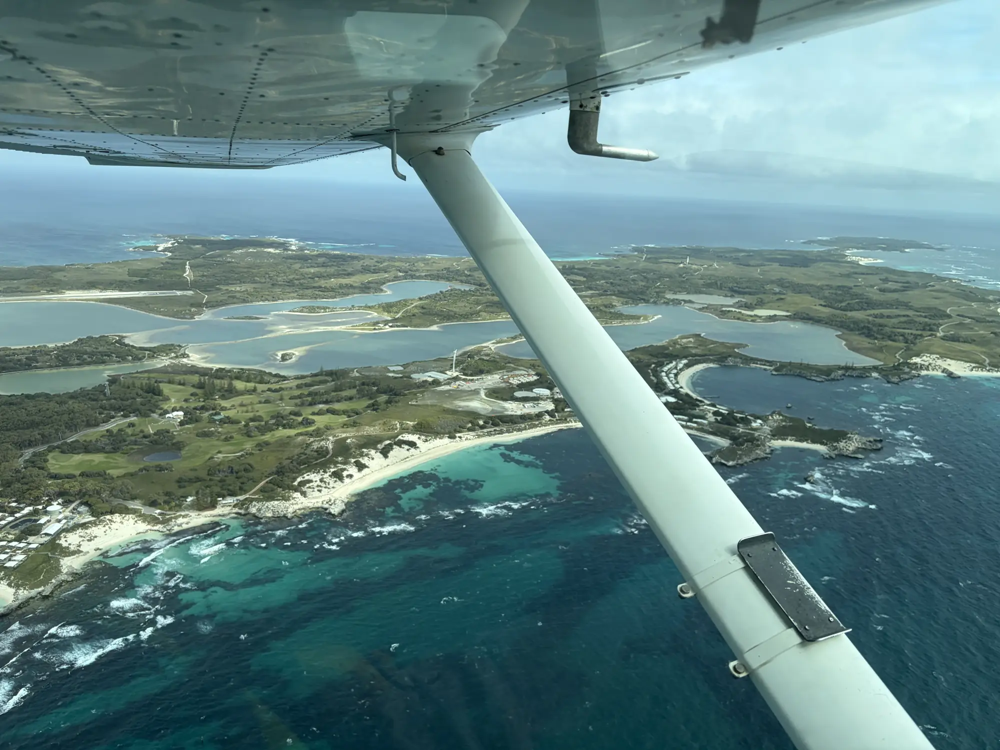 Turquoise water and an island seen beneath the wing of a light aircraft