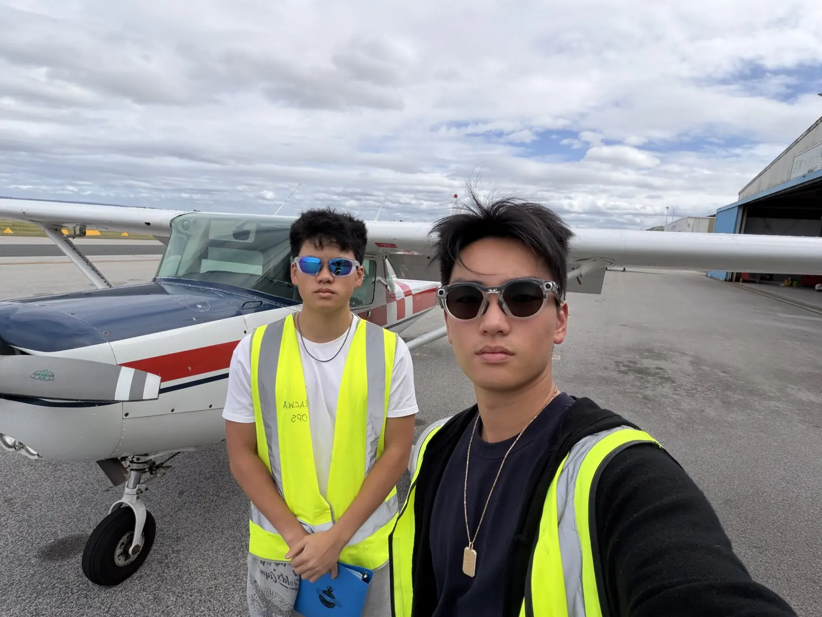 Two people in high-visibility vests beside a light aircraft