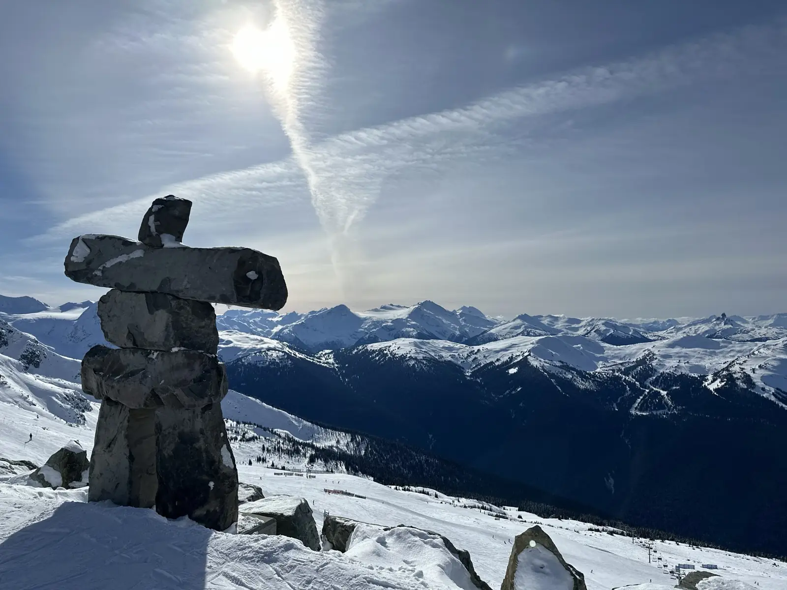 An inukshuk above the snow-covered mountains in Whistler